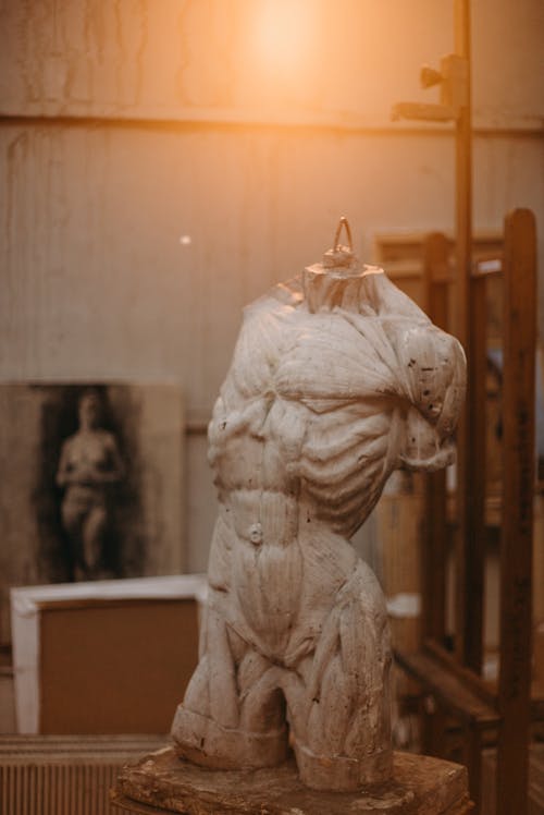 Белая бетонная статуя человека под лампочкой