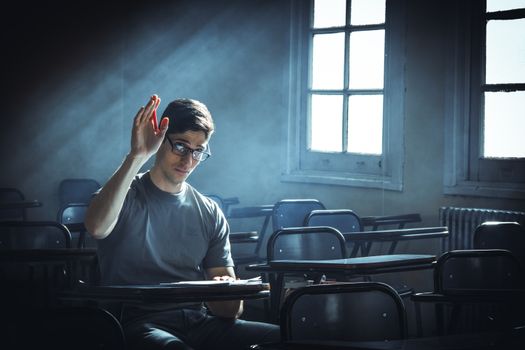 A student raises their hand in an empty classroom with dramatic lighting.