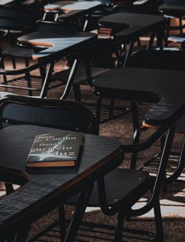 Dimly lit empty classroom focusing on a book on a desk, creating a moody educational atmosphere.