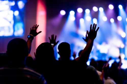 Free Engaged crowd enjoying a live concert with colorful stage lights and raised hands. Stock Photo