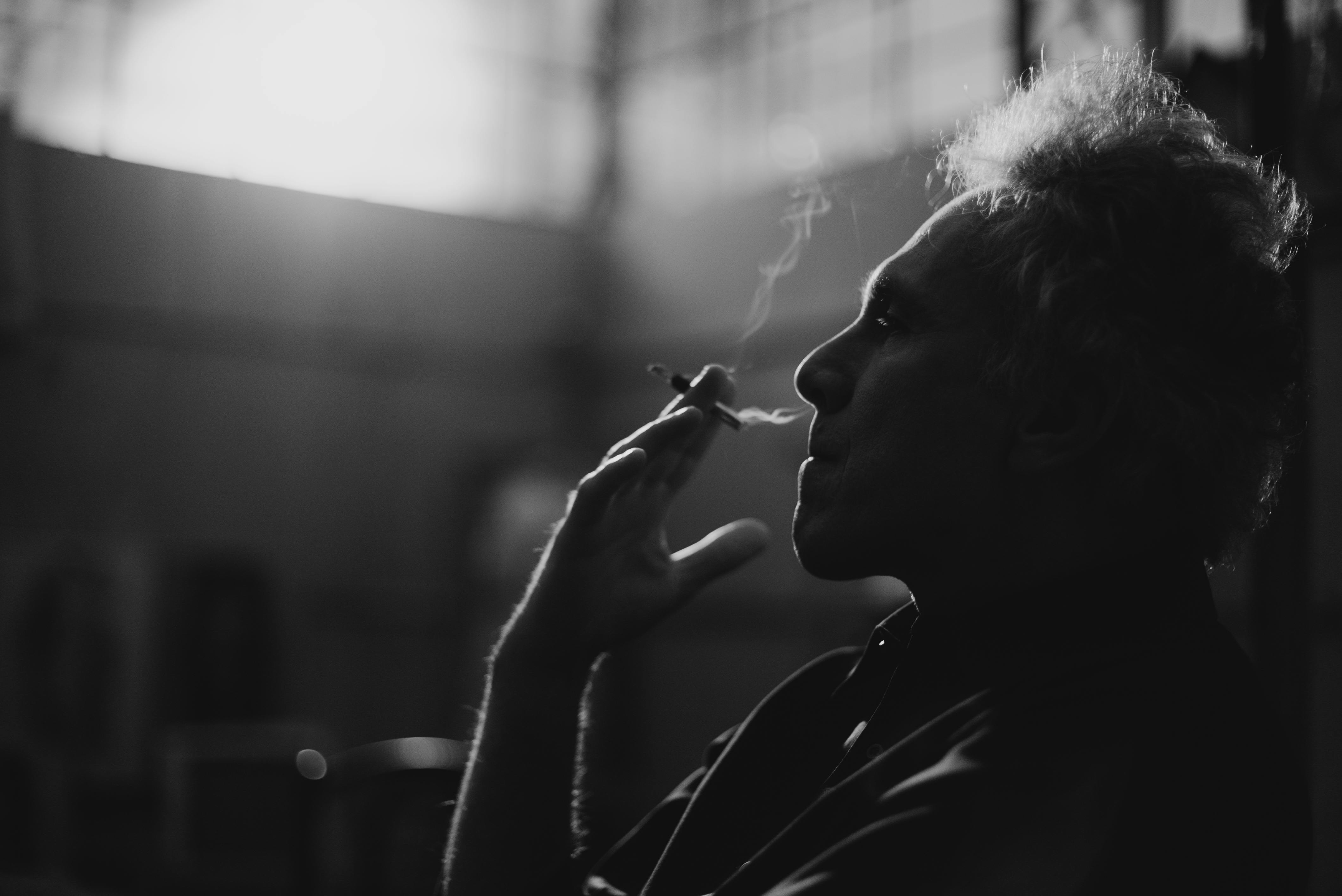 grayscale photo of man smoking cigarette