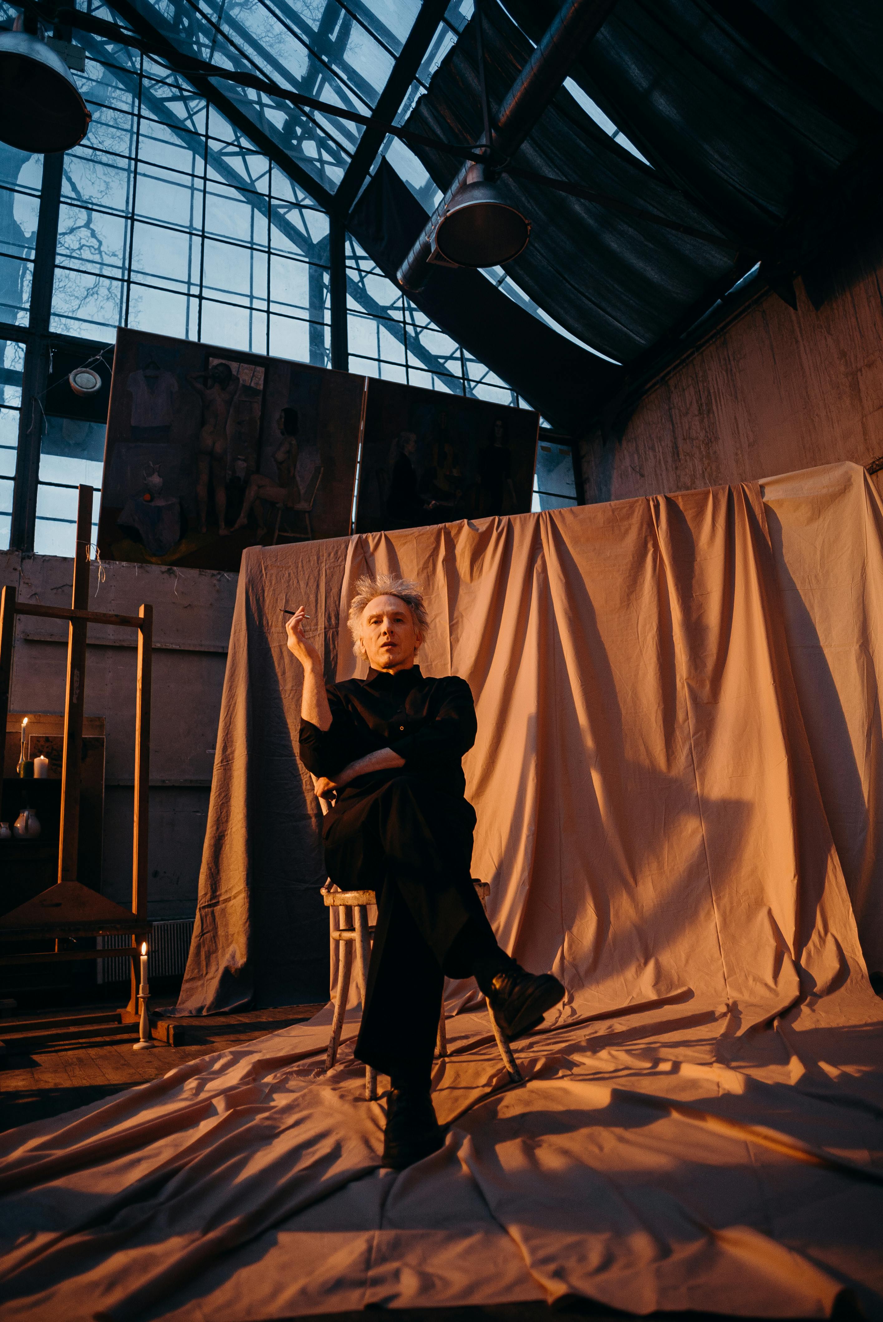 阳光明媚的工作室里，老年艺术家若有所思地坐着，周围都是艺术品