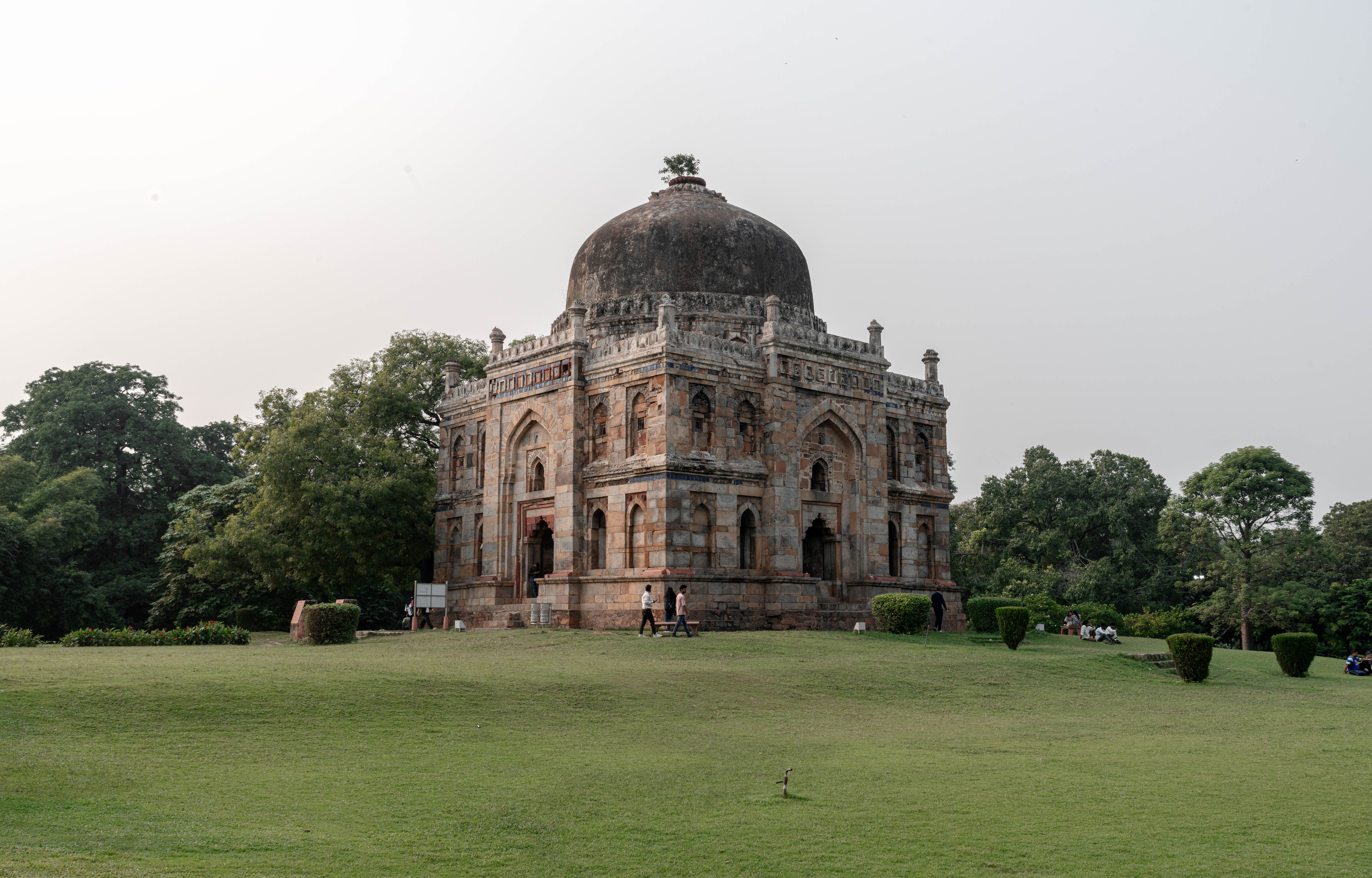 Tree-lined avenue in Lodhi Garden with a domed tomb behind