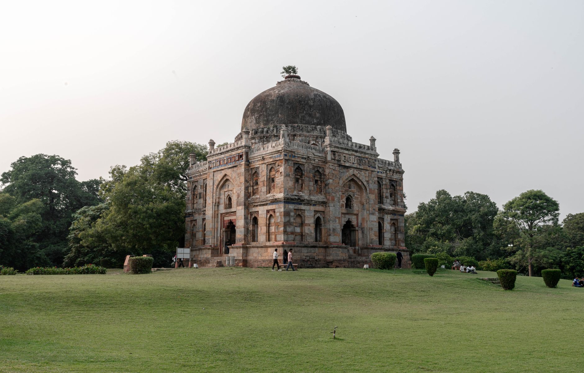 Tree-lined avenue in Lodhi Garden with a domed tomb behind