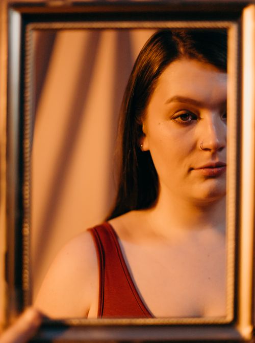 Free Captivating portrait of a woman with nose piercing reflected in a vintage mirror frame. Stock Photo
