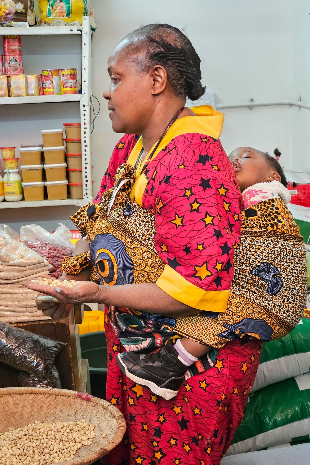 Woman in red traditional dress shopping with her baby on her back