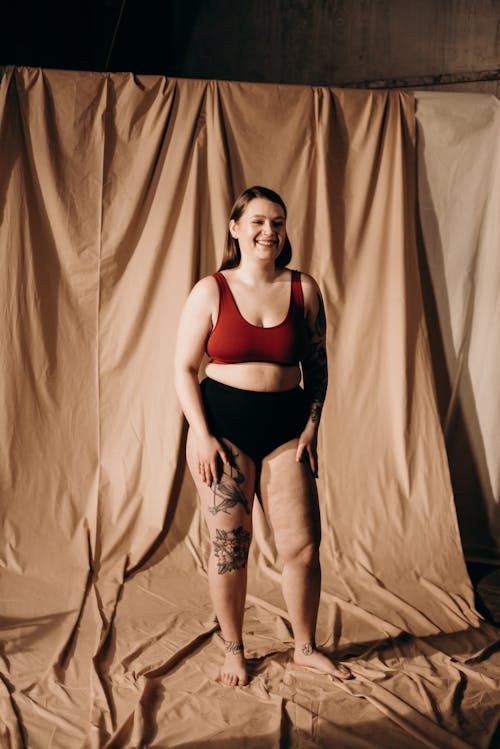 Woman in Red Sports Bra and Standing Beside Brown Curtain