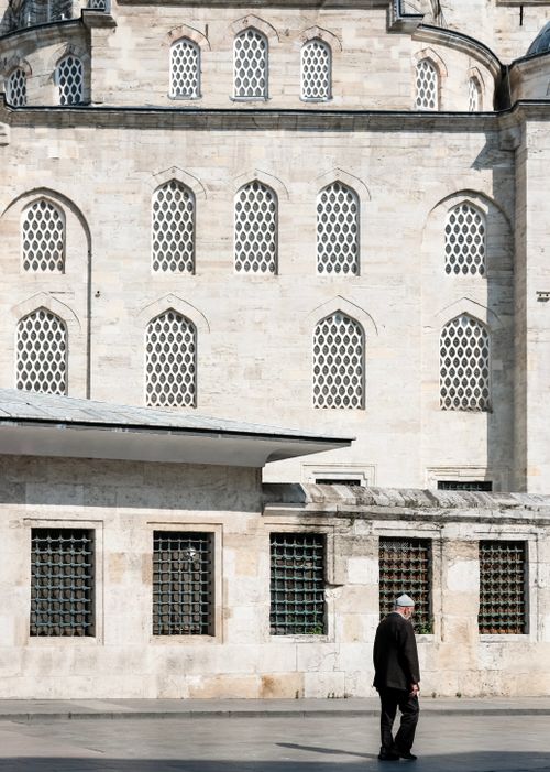 Free A person walks near a historic mosque's ornate windows, capturing Istanbul's charm. Stock Photo