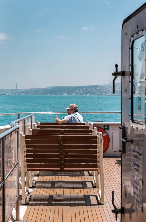 Free Man enjoying a ferry ride on the Bosphorus with a view of the sea and bridge under a clear blue sky. Stock Photo