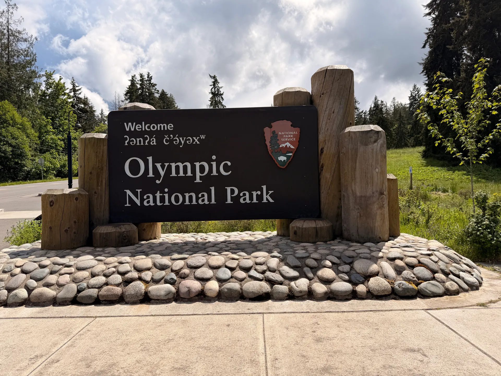 Olympic National Park entrance sign amidst lush greenery on a sunny day. Olympic National Park entrance sign amidst lush greenery on a sunny day.