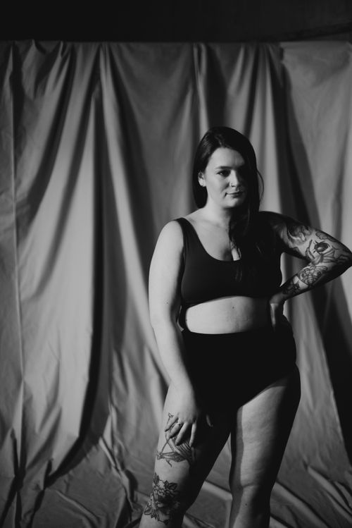 Free Monochrome portrait of a tattooed woman posing confidently indoors with a dramatic shadow play. Stock Photo