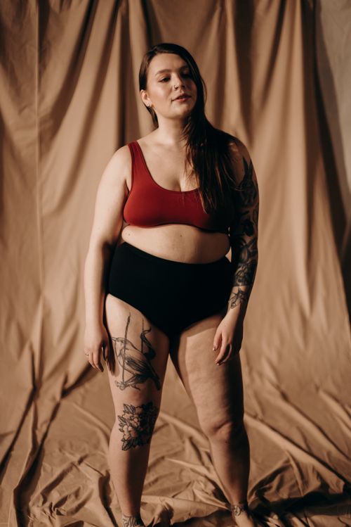 Free Tattooed woman posing confidently in a studio setting, embracing body positivity in stylish underwear. Stock Photo
