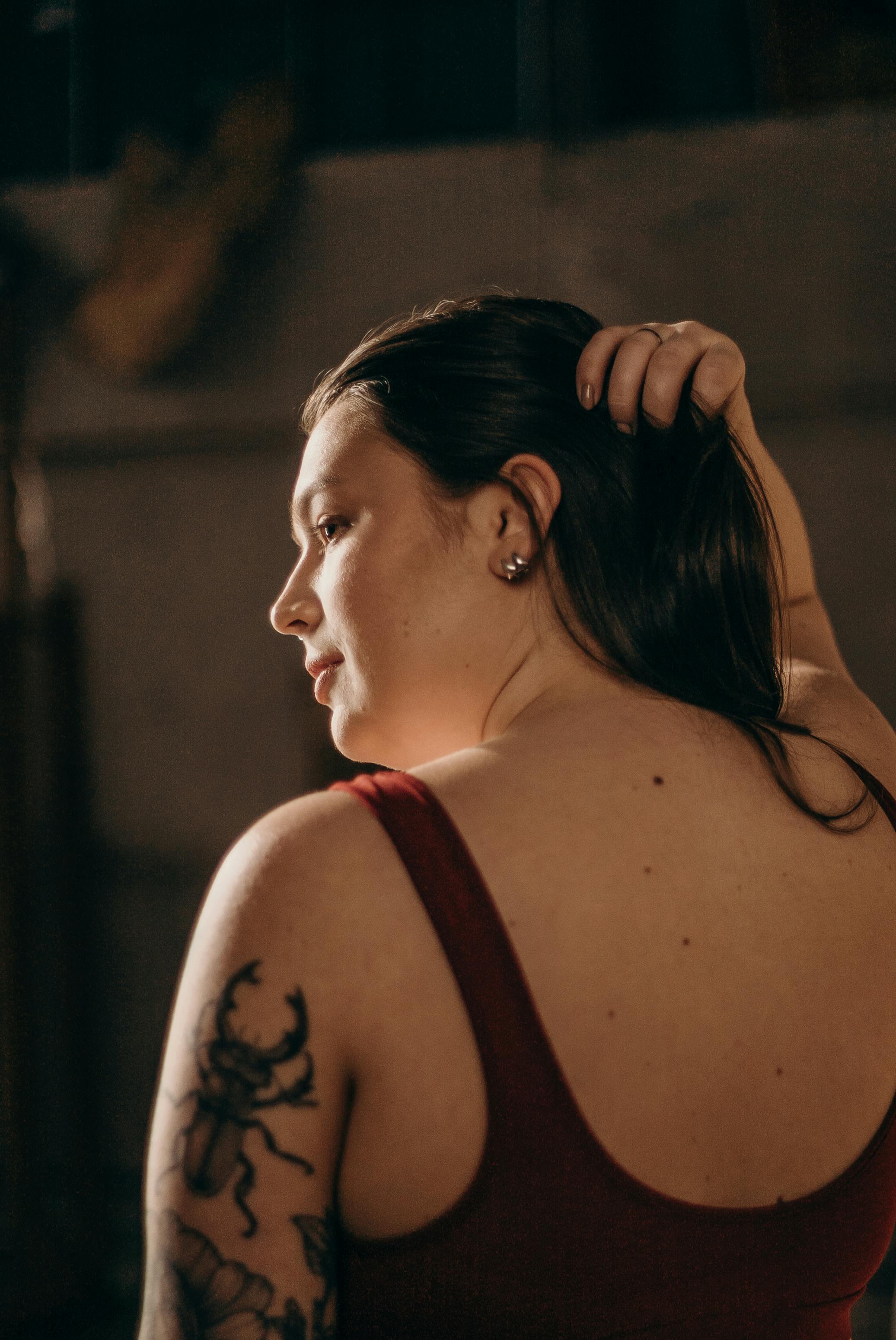 一位纹身女子以沉思的姿势，在工作室灯光下拍摄的艺术肖像