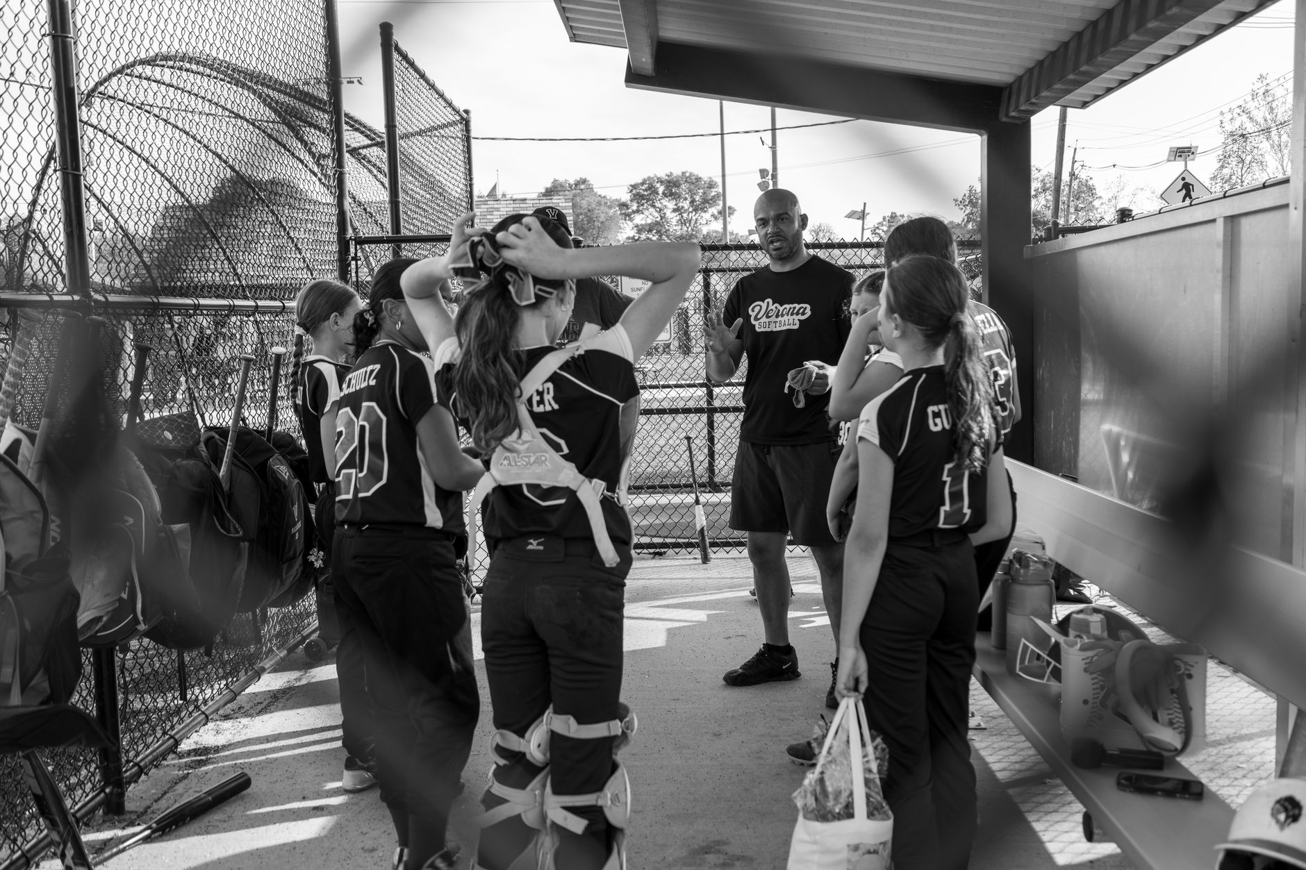 A youth softball coach gives a team talk to players in a dugout at Verona, NJ. Black and white photo.