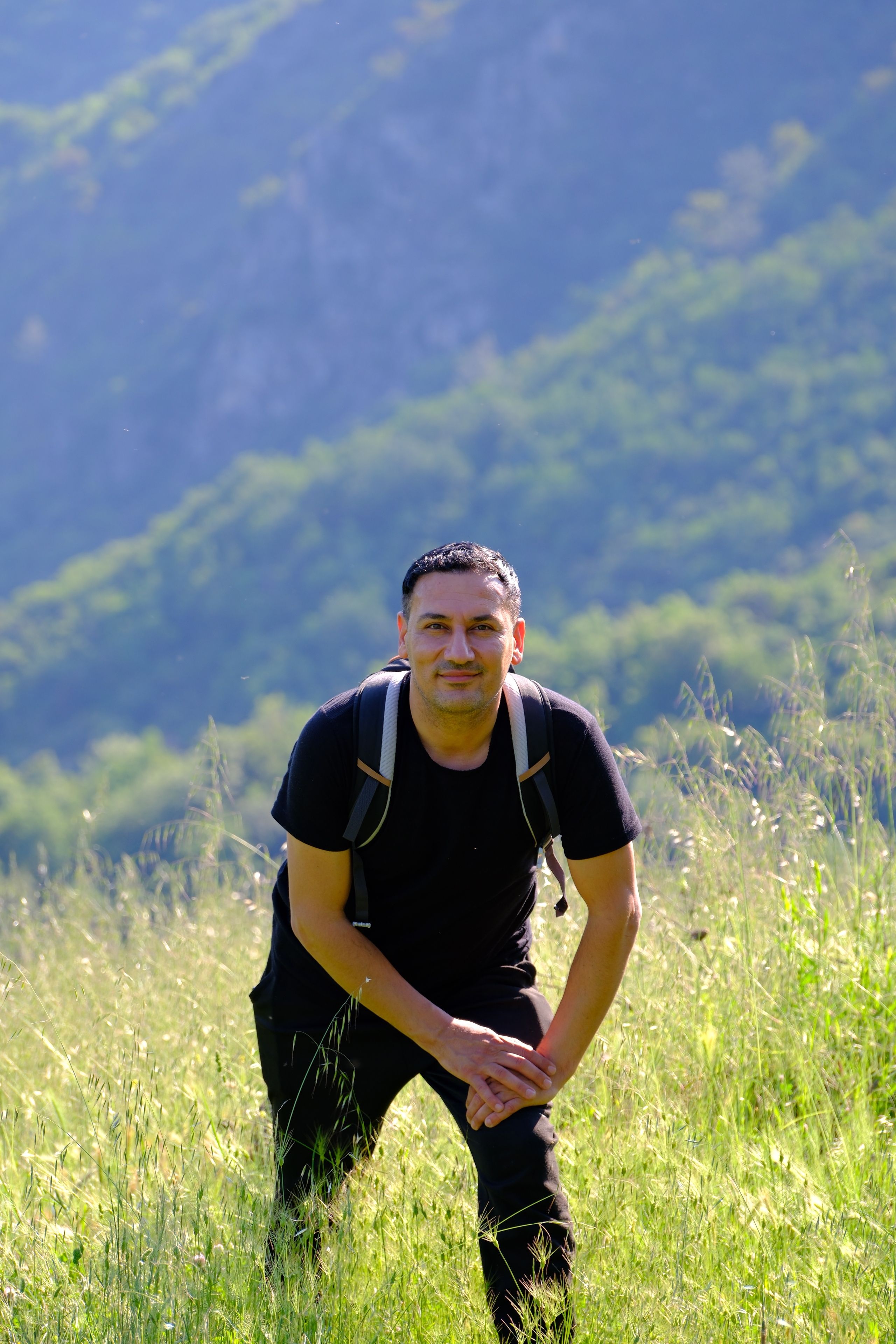 A hiker enjoying a bright day amidst lush grass and scenic hills in Keles, Bursa.
