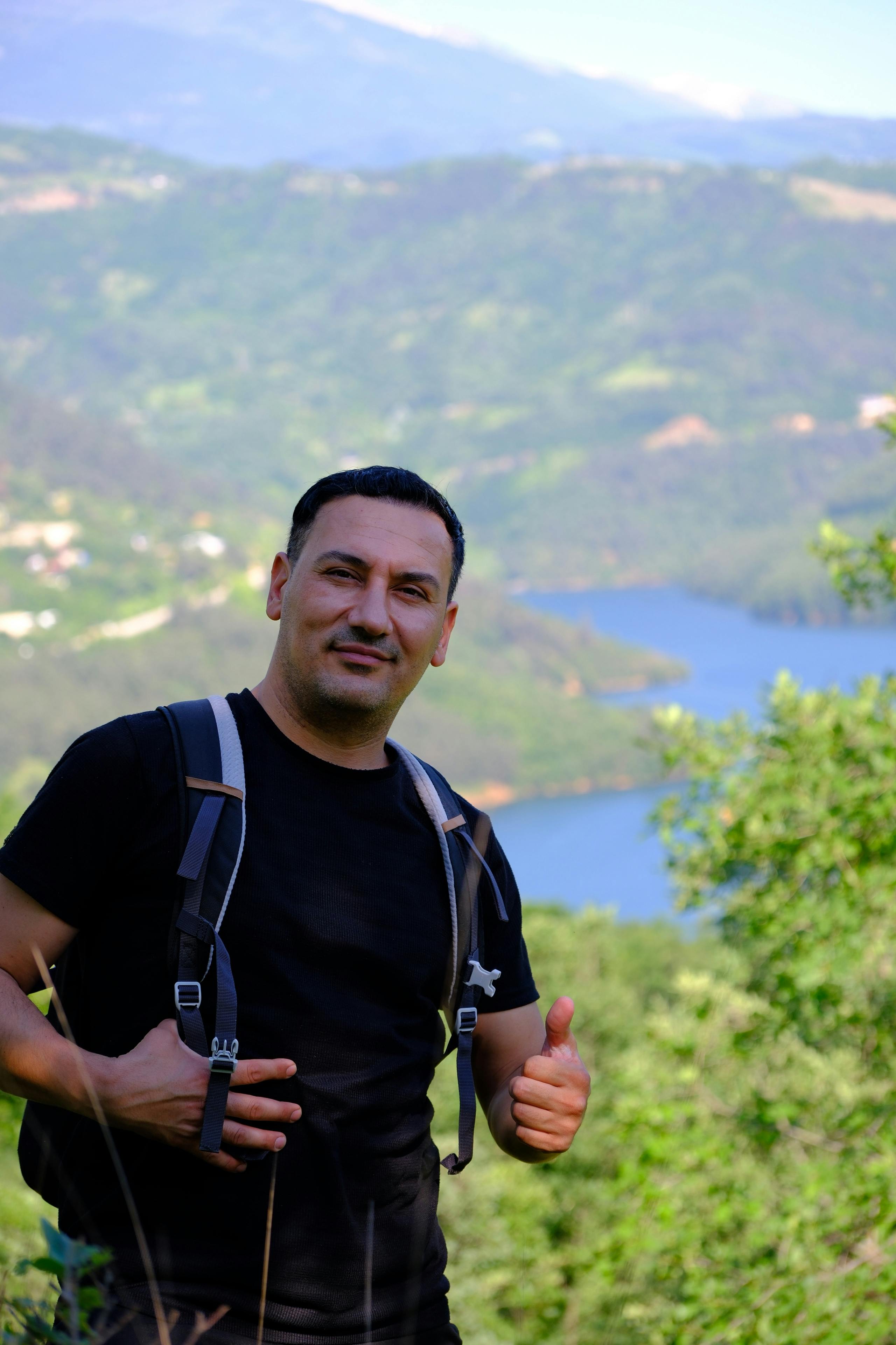 A man hiking in the mountains of Keles, Bursa with a scenic view of hills and water.