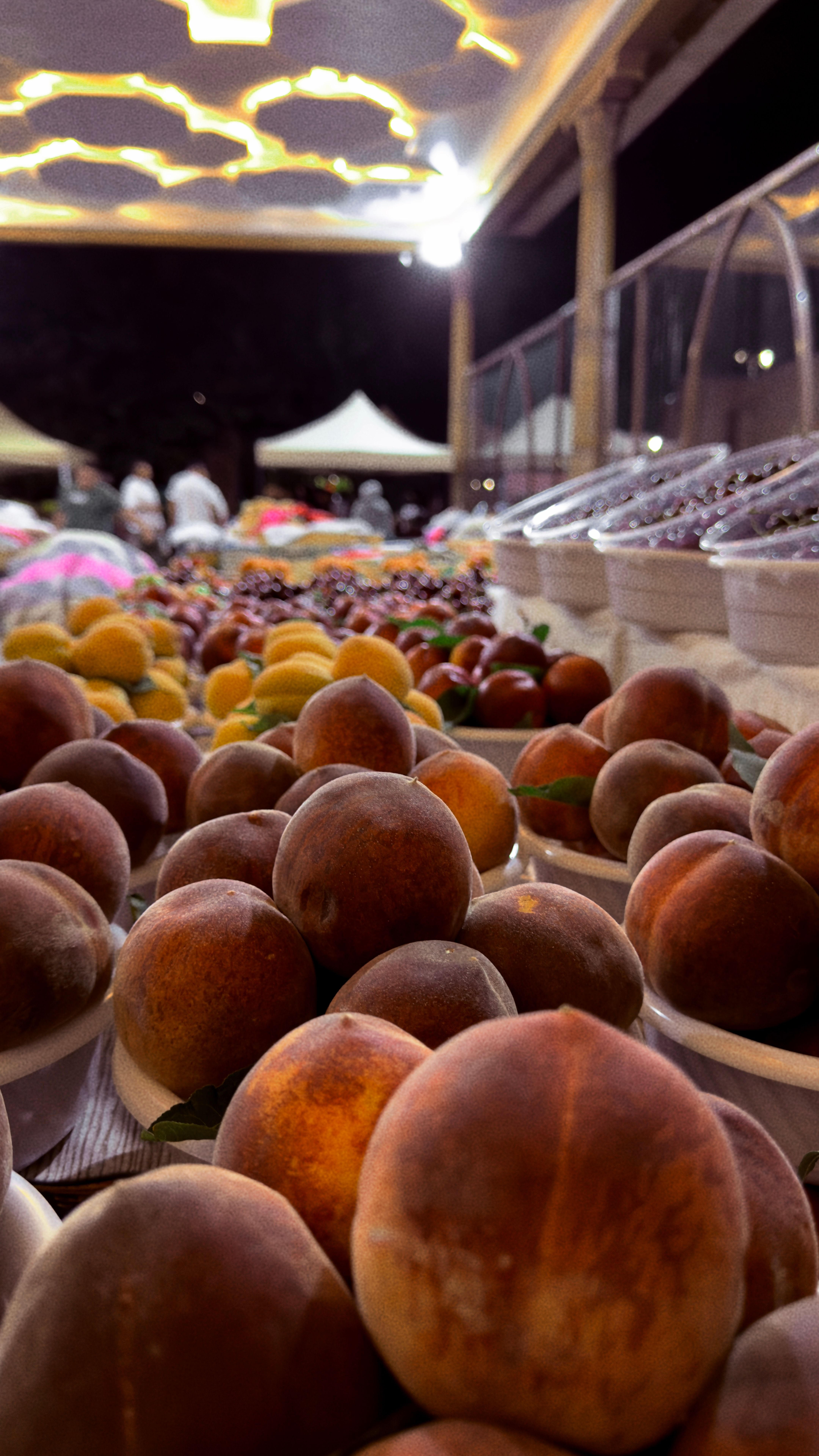 Fotomural Exhibición colorida de frutas frescas en un mercado nocturno de Uzbekistán, que muestra productos locales.