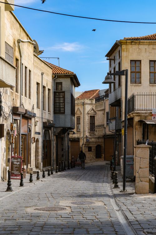 Free Quaint cobblestone street in Gaziantep, Türkiye with traditional buildings and a clear blue sky. Stock Photo