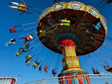 Thrilling swing ride attraction at Santa Cruz Beach Boardwalk under clear blue skies.