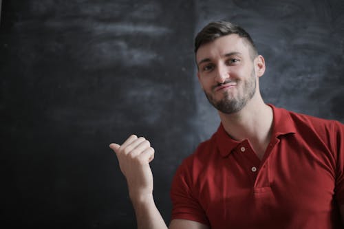 Man in Red Polo Shirt Standing Beside Chalk Board