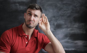 Man in Red Polo Shirt Sitting Near Chalkboard