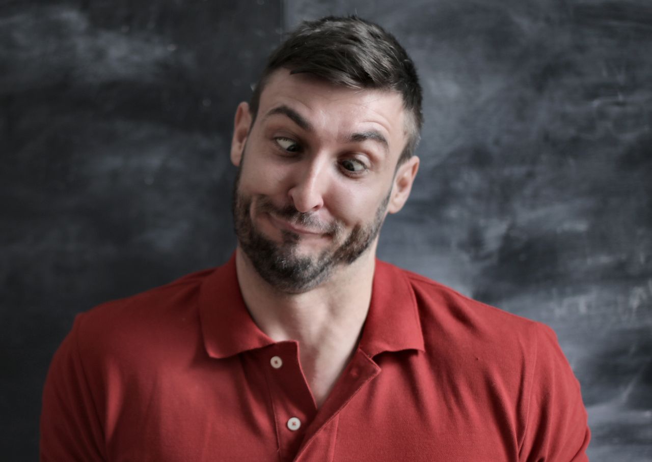 amusing portrait of a man making a wacky facial expression in a red po