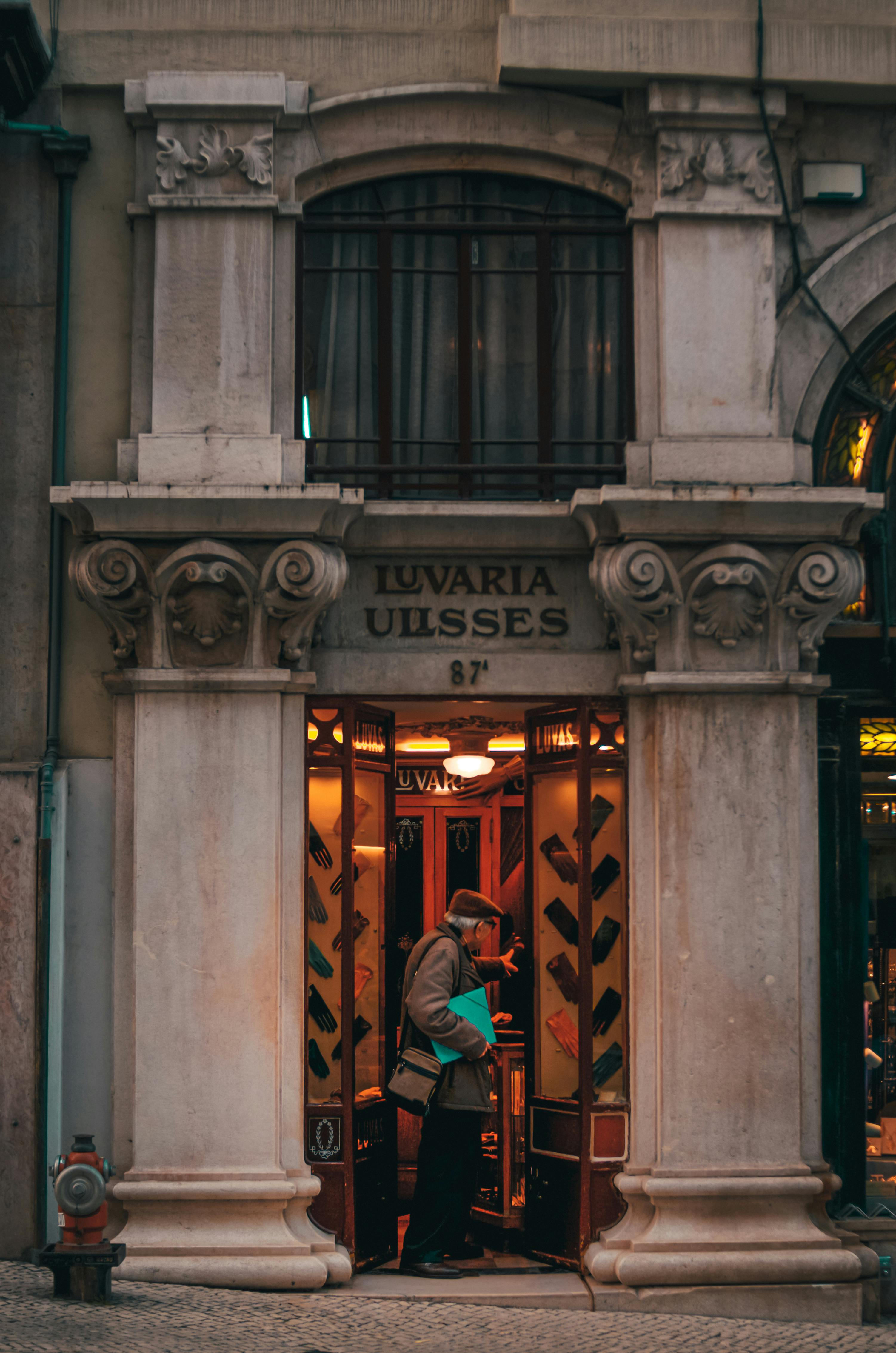 Free A vintage shop entrance with classical columns and a customer browsing inside. Stock Photo