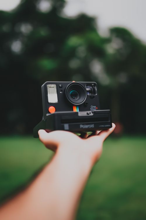 Free Close-up of a hand holding a Polaroid camera outdoors in São Paulo, Brazil. Stock Photo