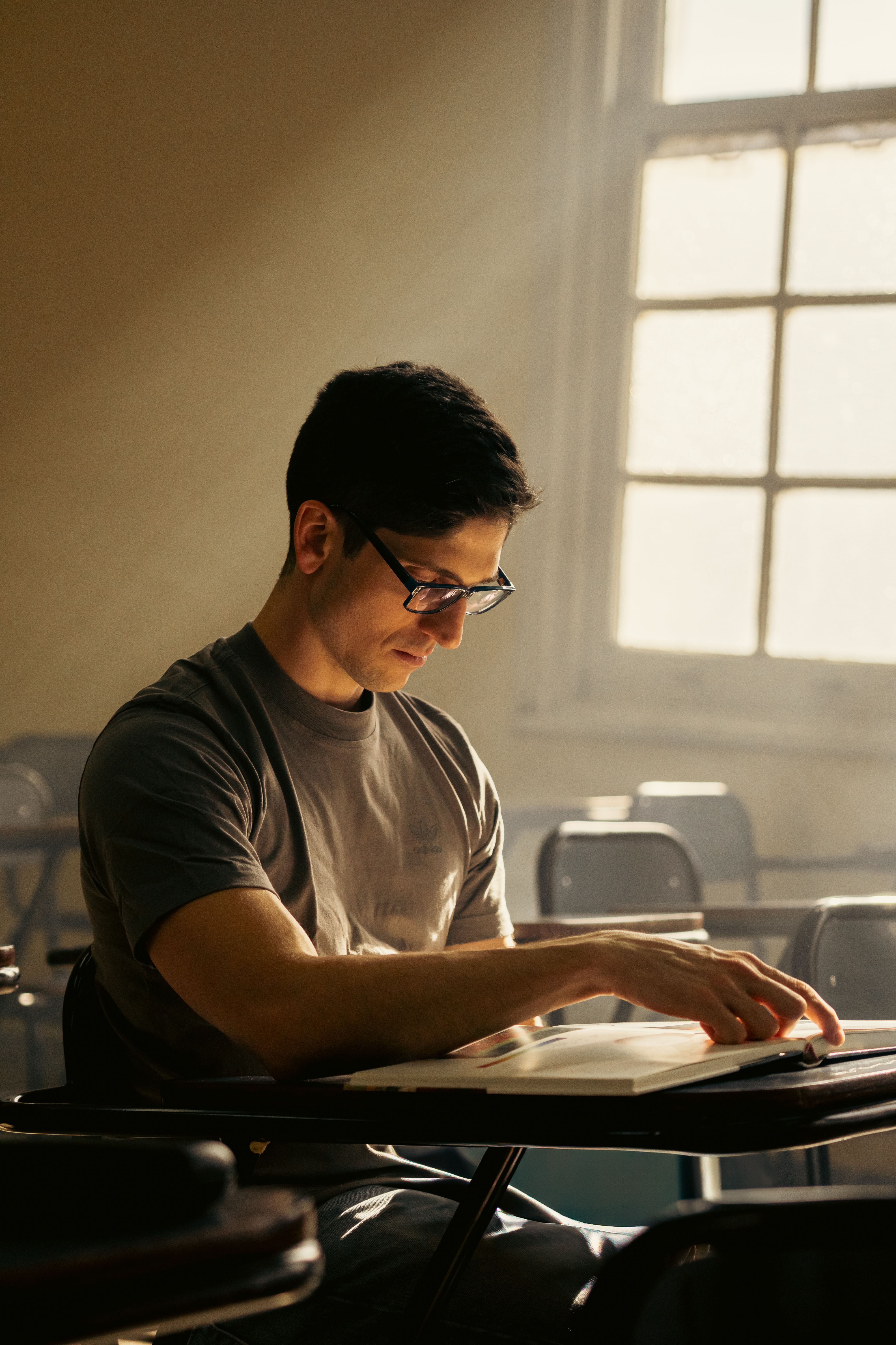 A focused university student reads in a sunlit classroom in Buenos Aires.