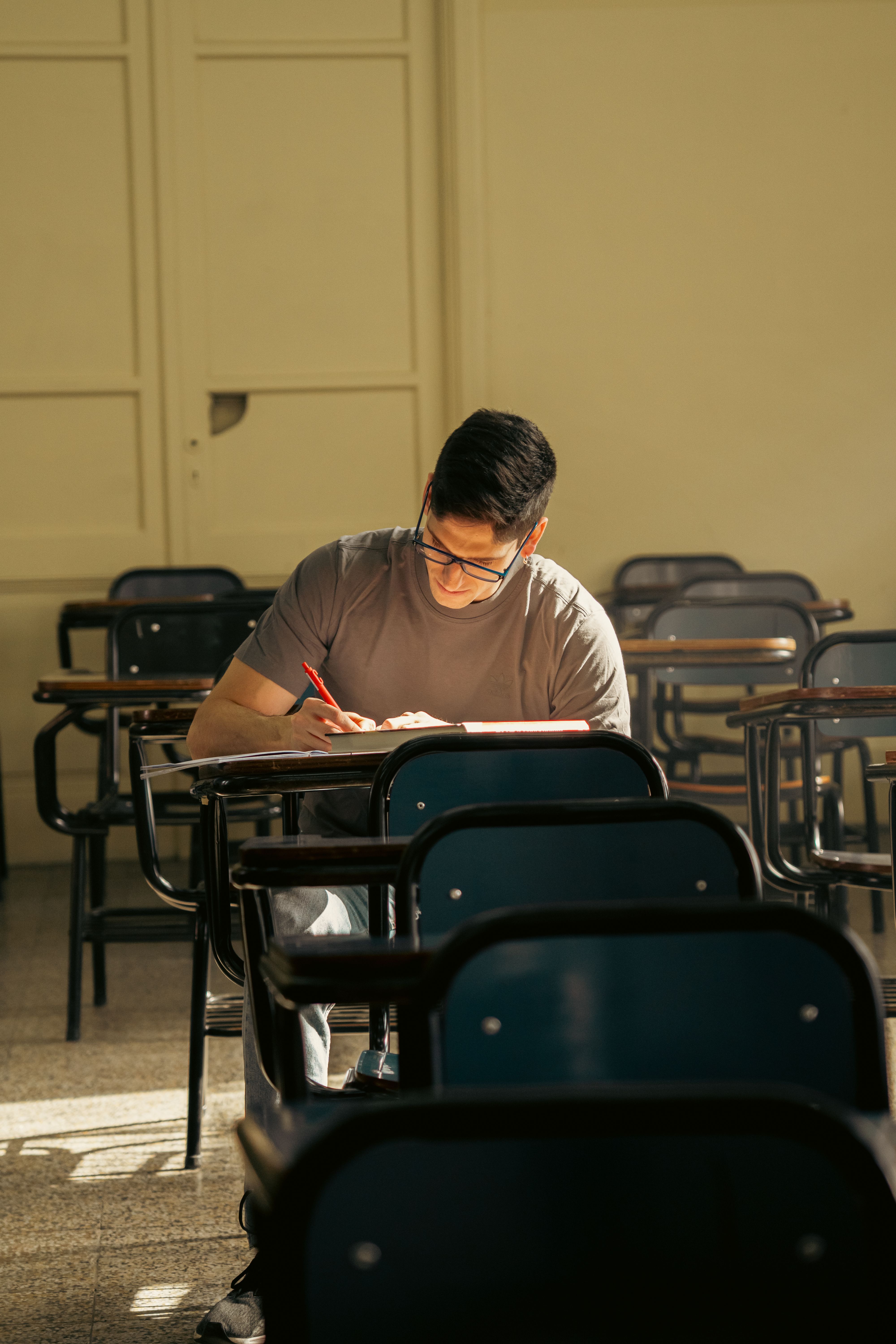 A university student studying alone in a sunlit classroom in Buenos Aires, Argentina.