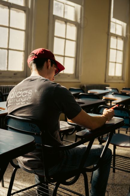 A university student focuses on writing in an empty, sunlit classroom in Buenos Aires. A university student focuses on writing in an empty, sunlit classroom in Buenos Aires.