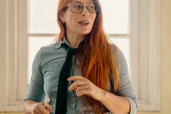 A female teacher passionately engages with her students in a bright classroom setting.