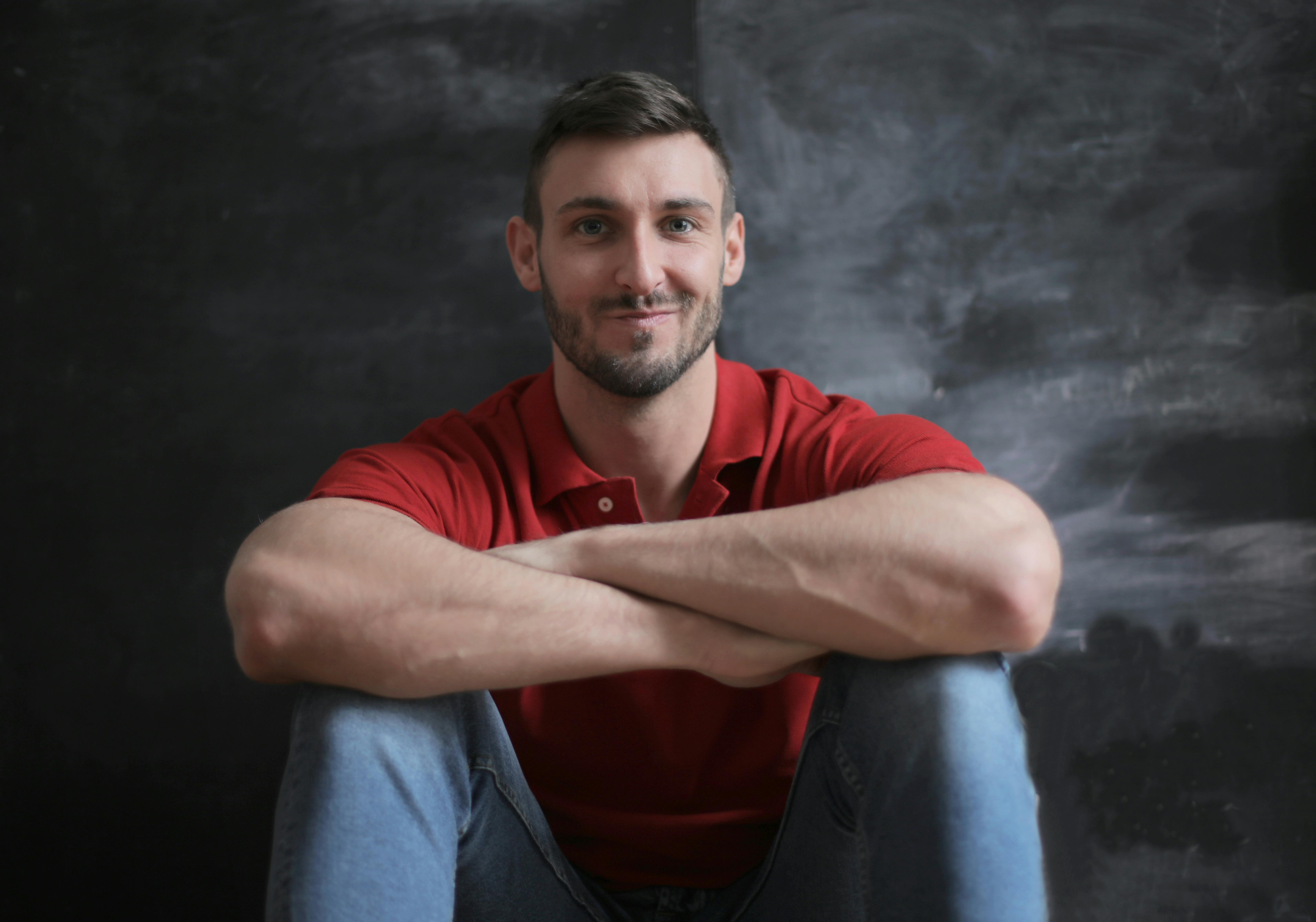 man in red polo shirt and blue denim jeans