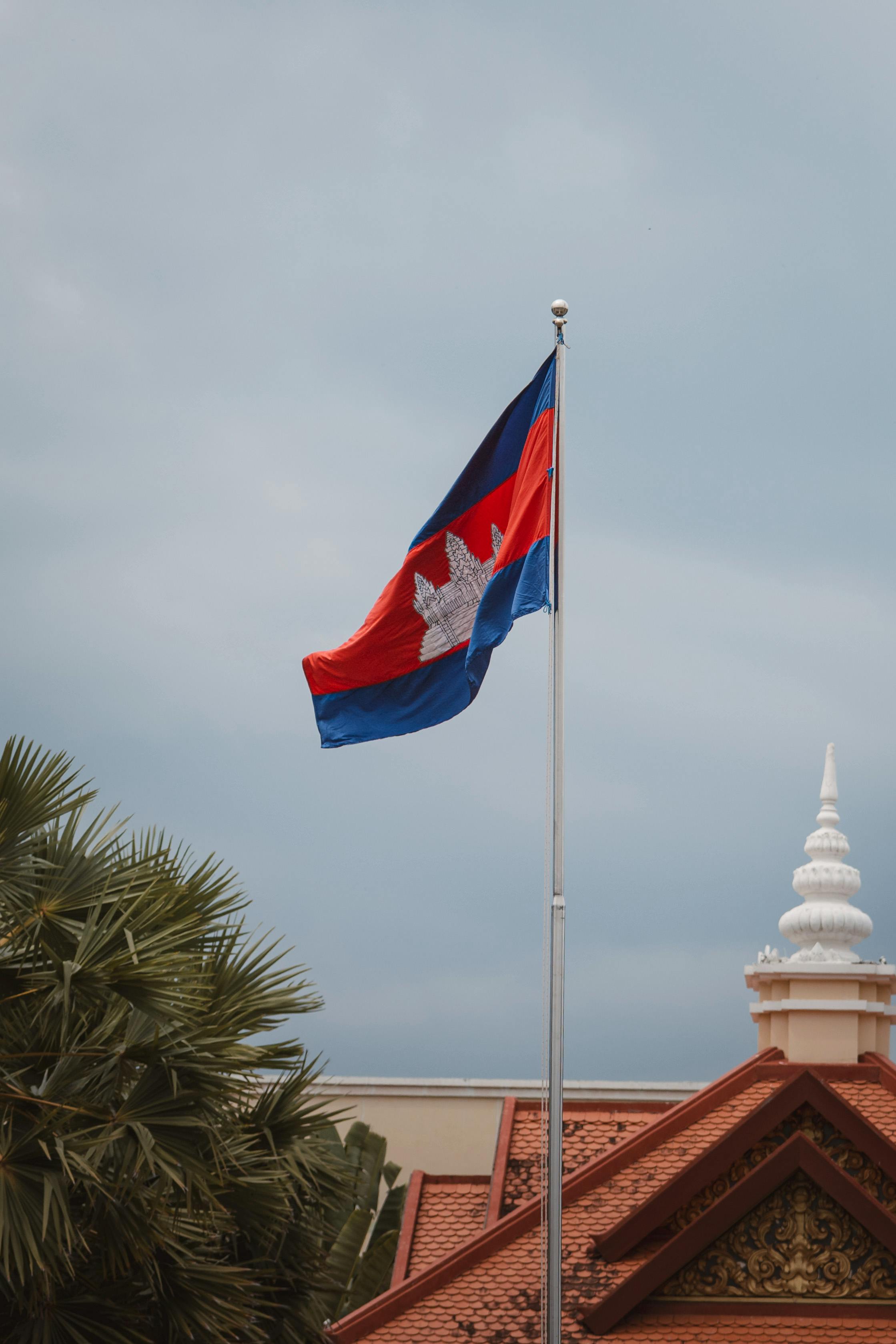 Image of the Cambodian national flag waving near traditional architecture in Phnom Penh.