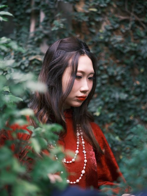 Free Portrait of a woman in red traditional dress surrounded by greenery. Stock Photo
