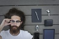 一个留着胡子的男人躺在木板上，手里拿着小工具和配件