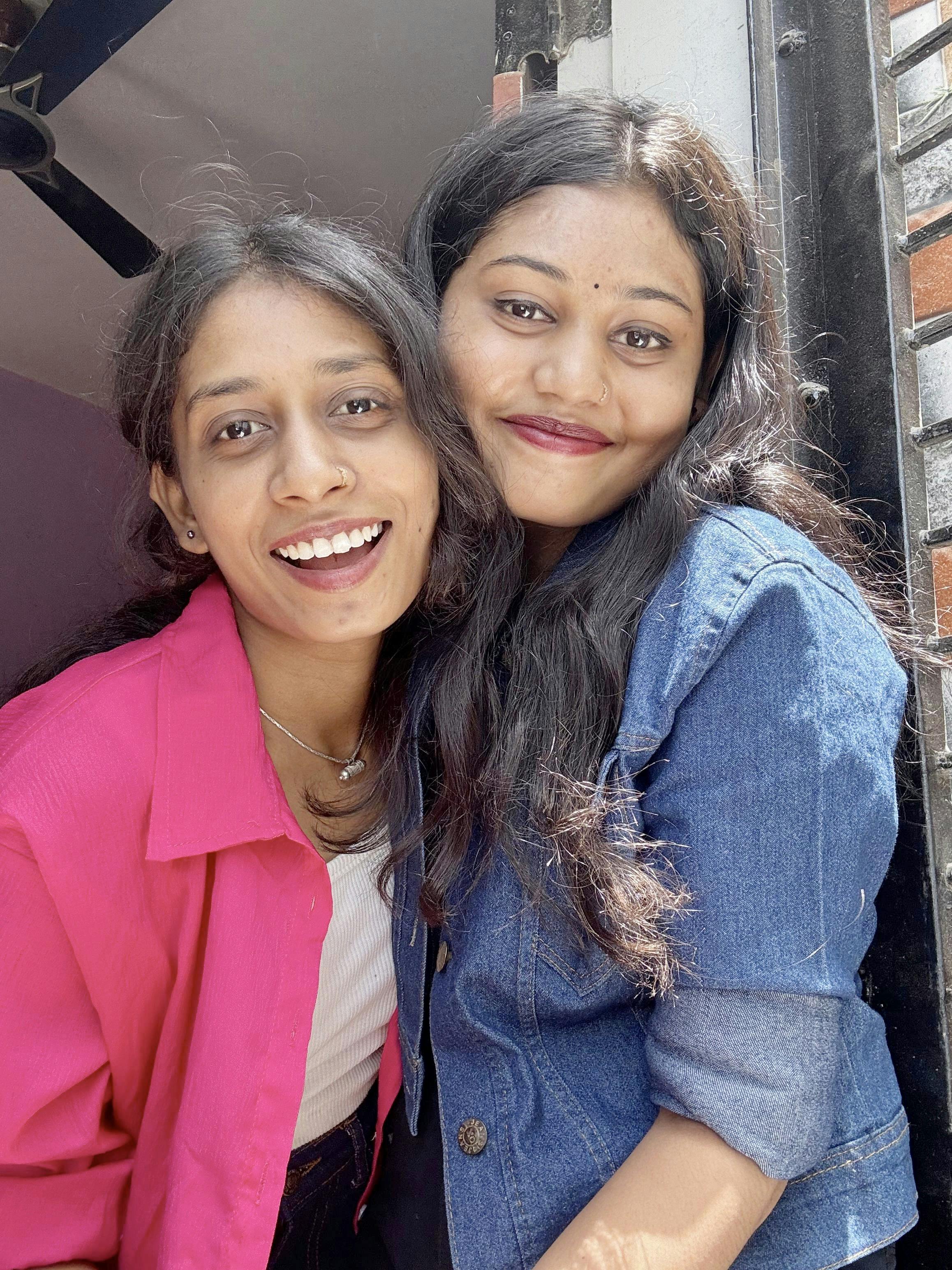 Two friends happily posing for a picture outdoors on a sunny day.
