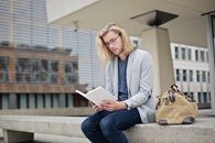 一名年轻男子在大学校园的长凳上看书