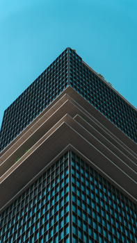 Low angle view of a modern skyscraper with a grid pattern facade against a clear blue sky.
