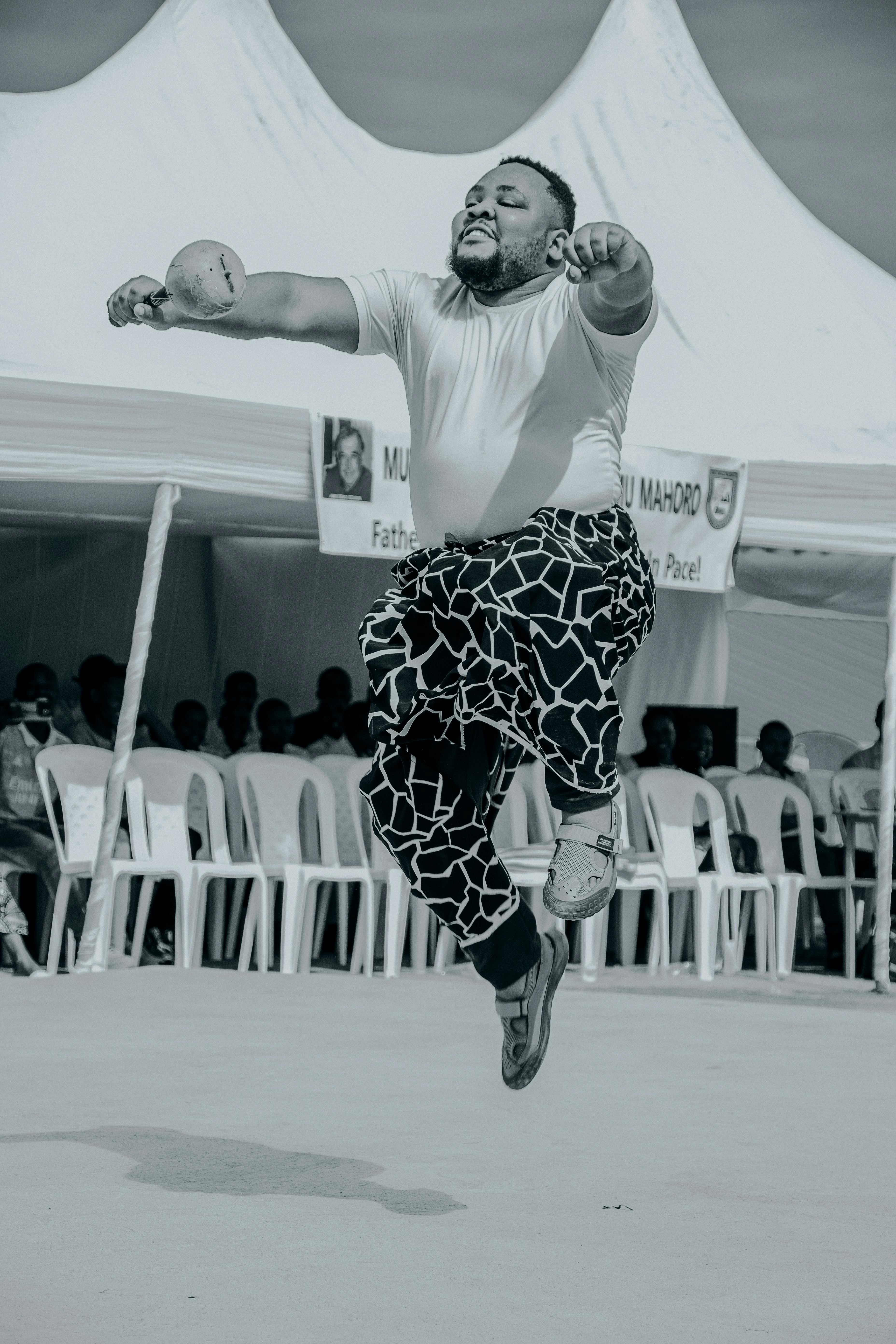 Energetic traditional dance captured during an outdoor cultural event with tents and spectators.