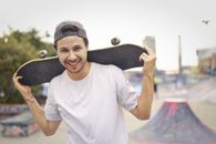 Man in White Crew Neck T-shirt While Holding Black Skateboard