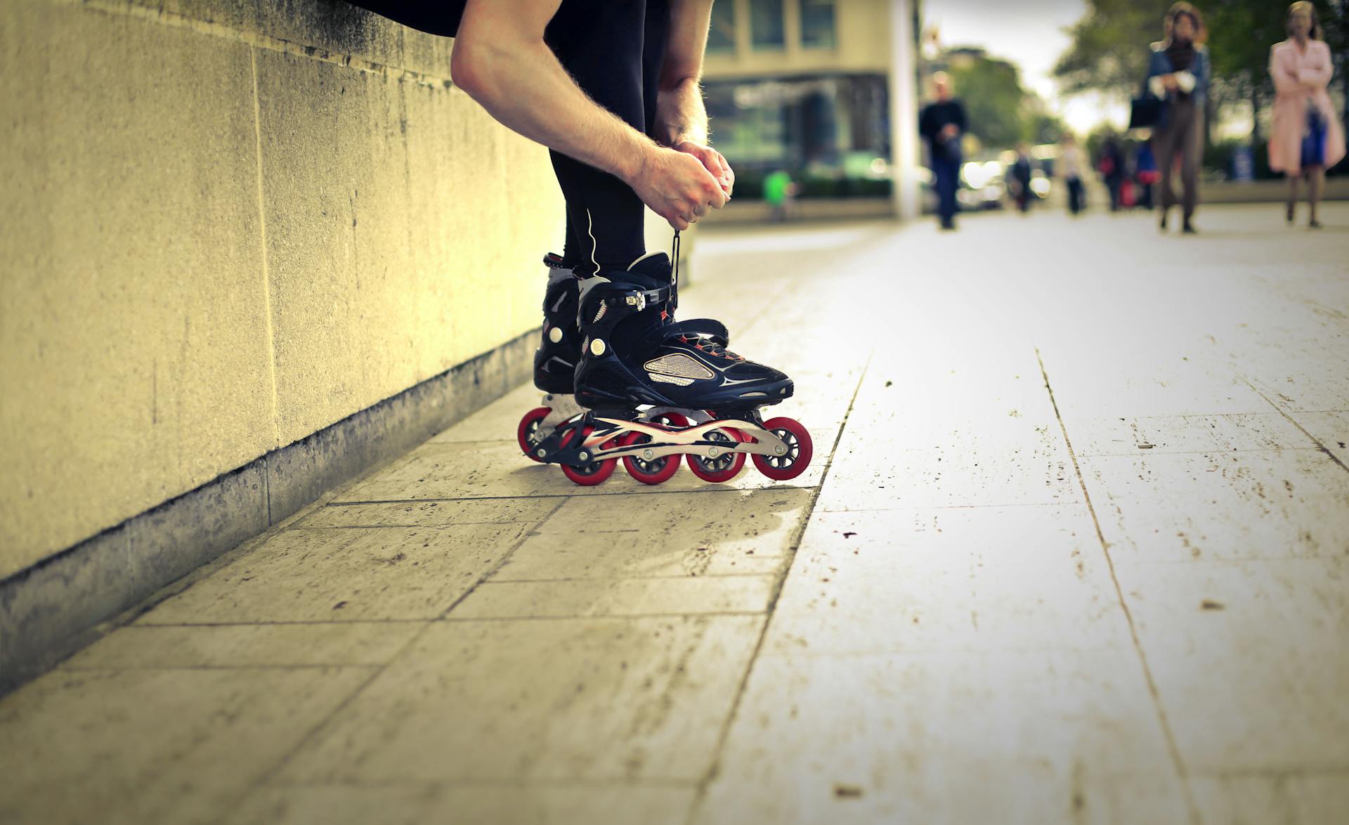 Focused skater adjusting roller blades in a dynamic urban city park setting.