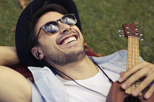 Man in White Tank Top Lying on Green Grass Field