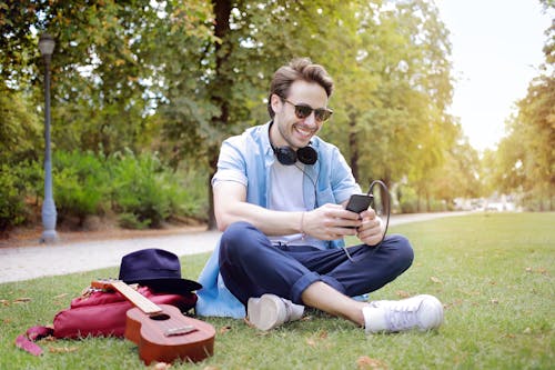 Mann Mit Smartphone Sitzendem Grasfeld