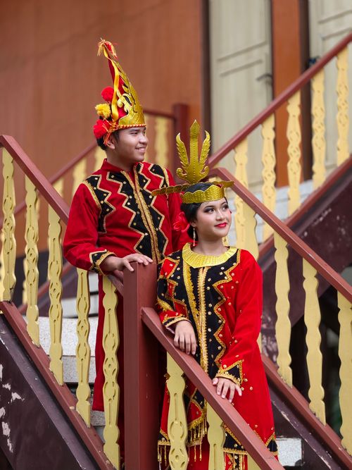 Free Festive Indonesian couple in traditional dress on a staircase in Jakarta, Indonesia. Stock Photo