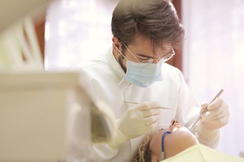 Free Dentist in face mask conducting a dental examination with tools in clinic setting. Stock Photo