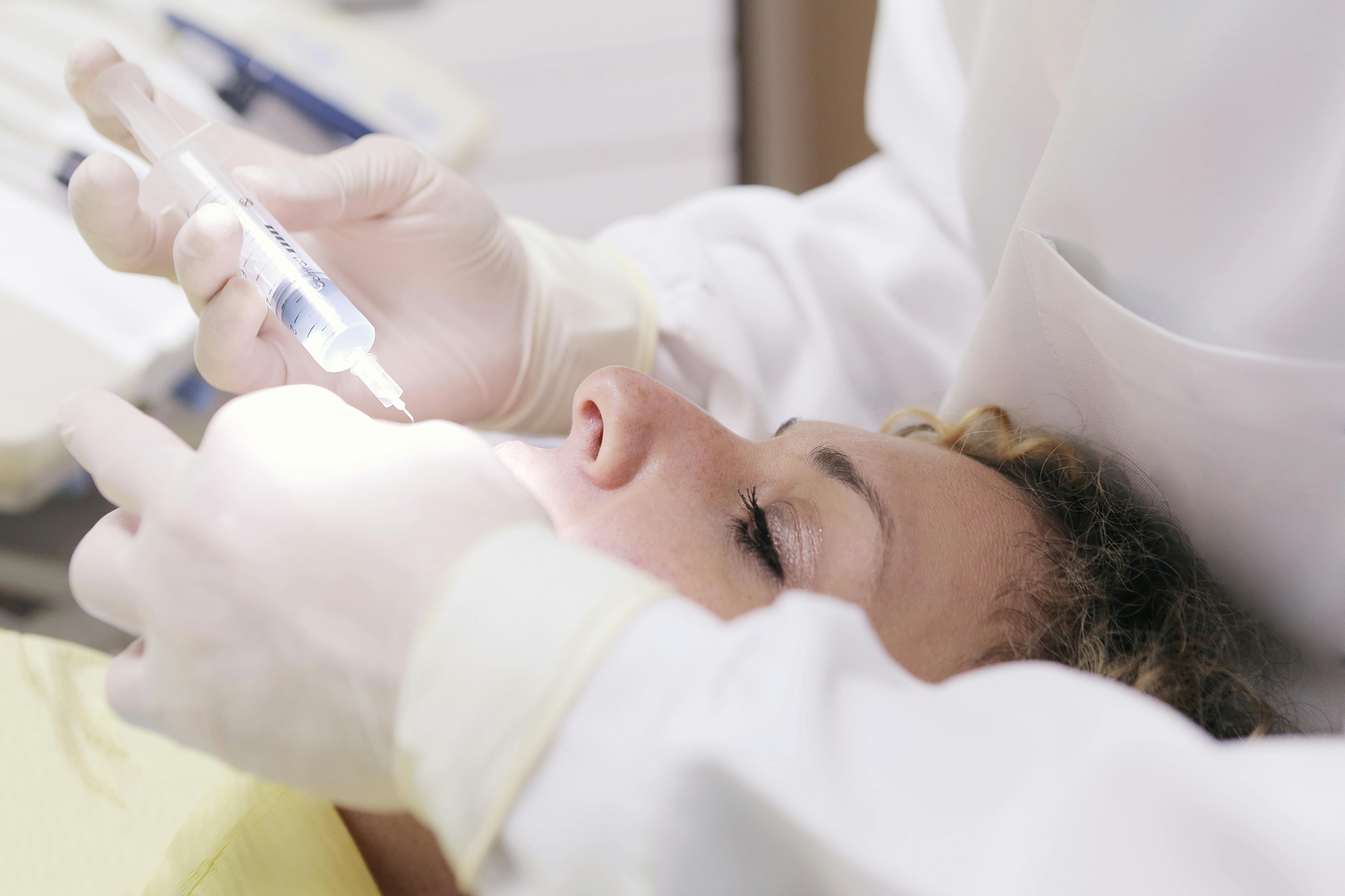 Free Close-up of a dental professional administering an anesthetic injection to a patient in a clinic. Stock Photo