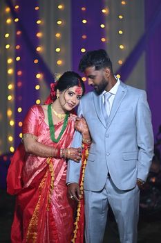 A joyous Indian couple in traditional attire at a vibrant wedding celebration.