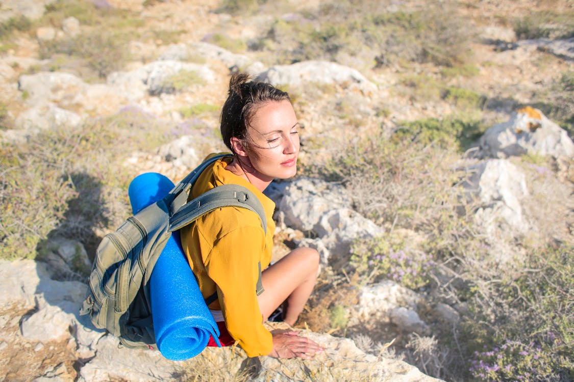 Girl in Yellow Long Sleeve Sitting On Brown Rock