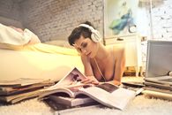 Woman Listening to Music While Reading a Book
